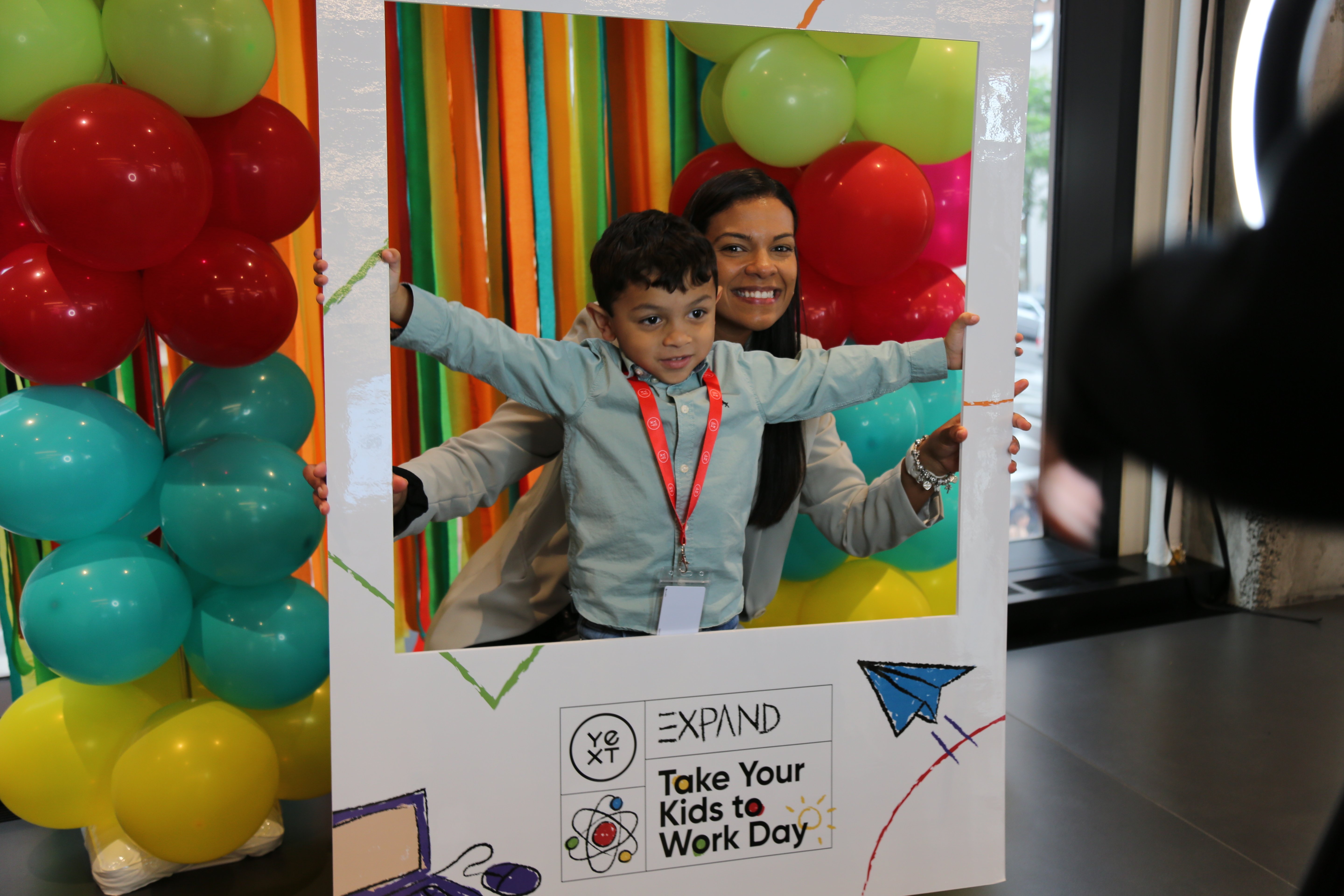 Candid photo of a mom and her son at a photo booth setup for Take  Your Kids to Work Day.