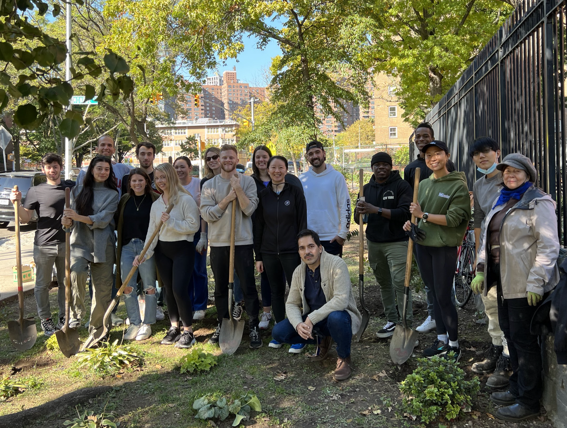 Group photo of Yext team members volunteering at a gardening event, holding shovels.