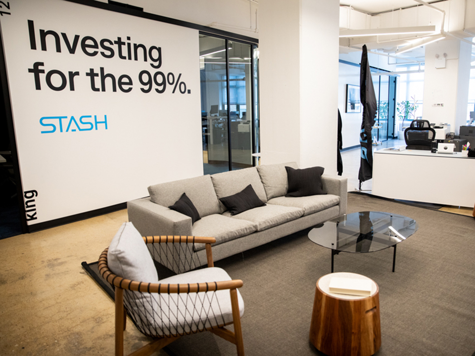 Stash office with its logo mural and "Investing for the 99%" slogan, as well as couches