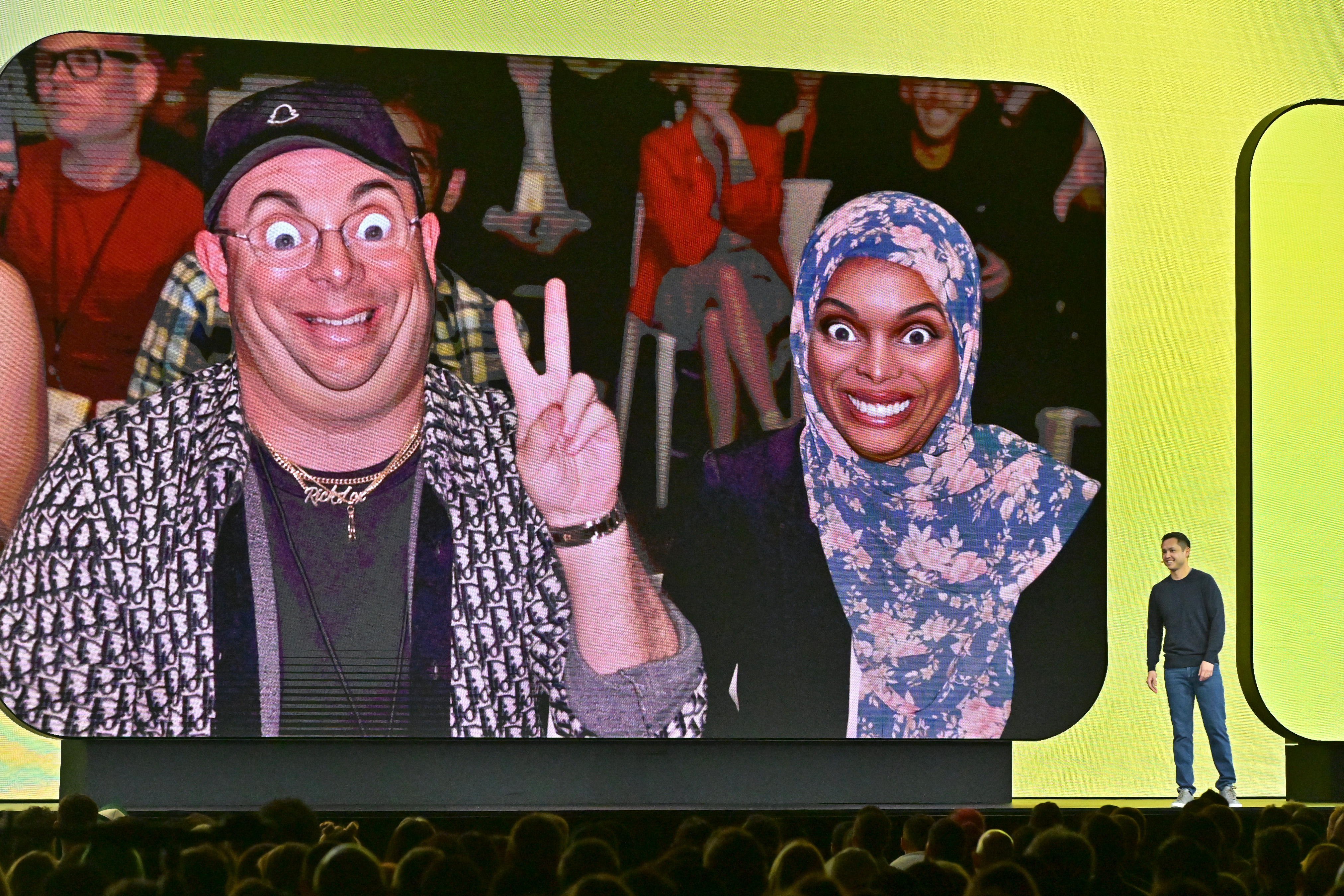 Photo from SPS 2023 of two audience members with AR filters on the large screen