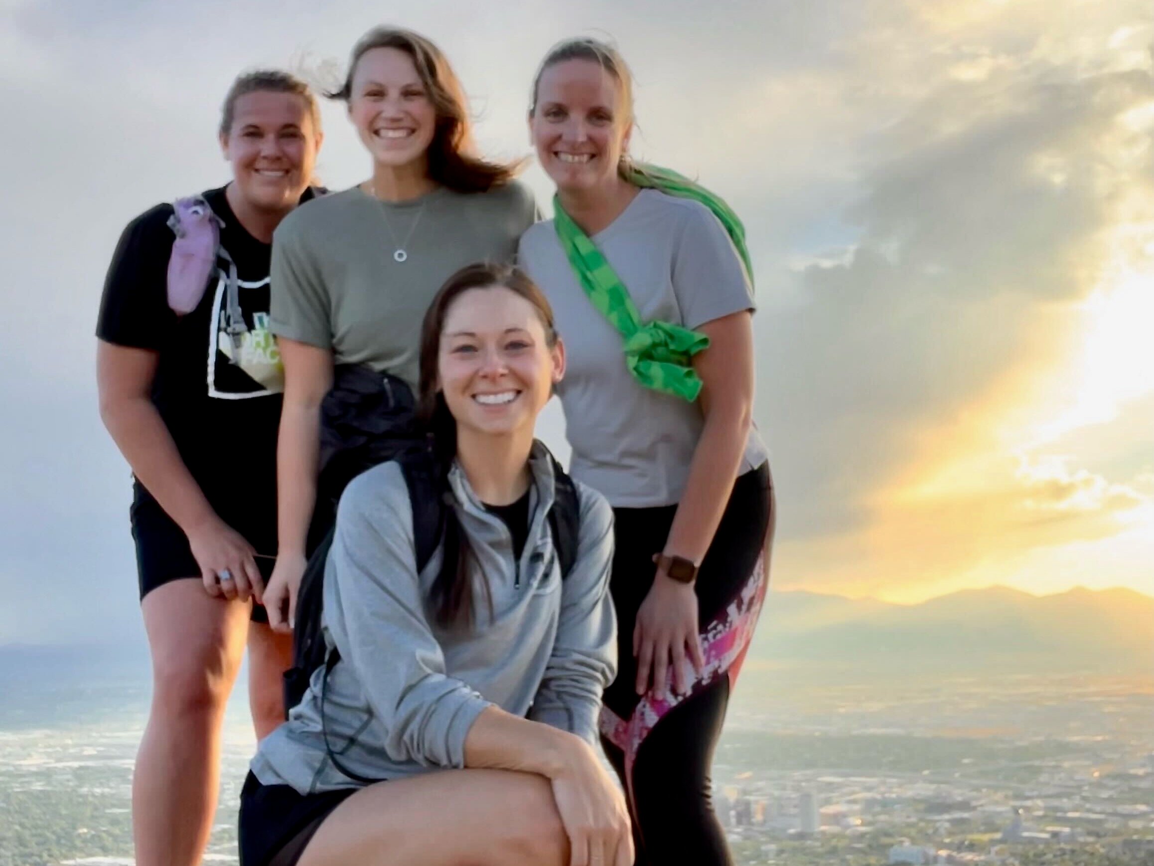 Four Navan women employees standing on a hill overlooking an urban landscape at sunset