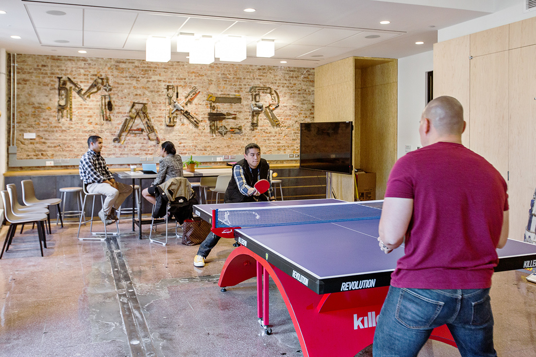 Capital One team members playing ping pong in the office game room