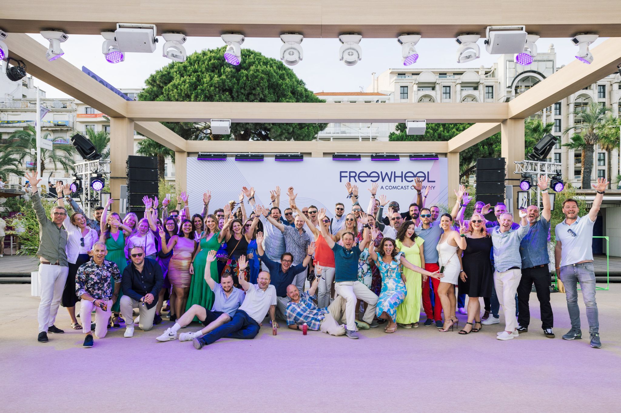 Large group photo of Freewheel team members in an outdoor stage setup at Cannes, France.