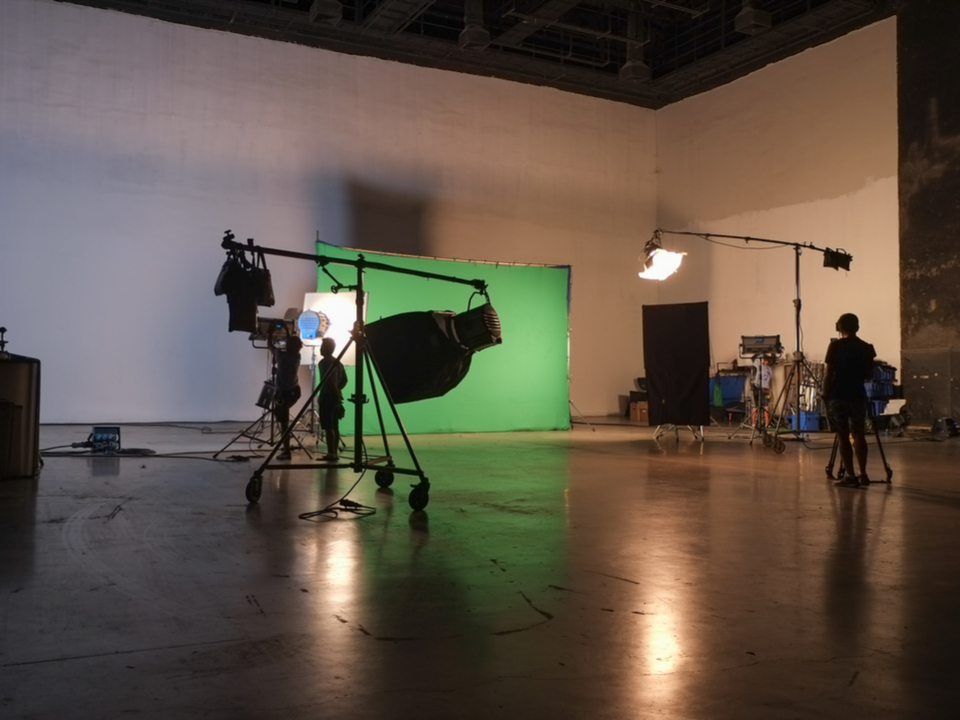 A movie studio with a green screen, lights, and cameras