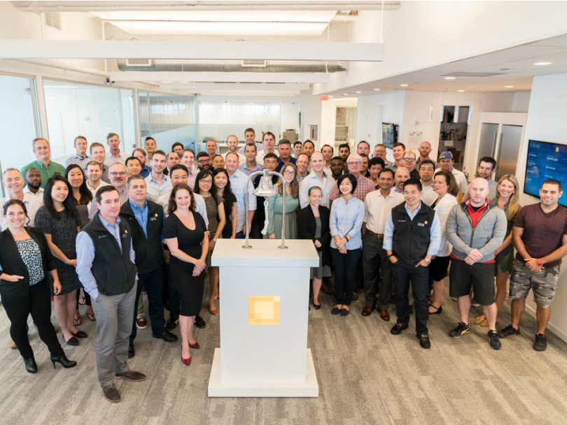 A large group of IEX employees pose in the office.