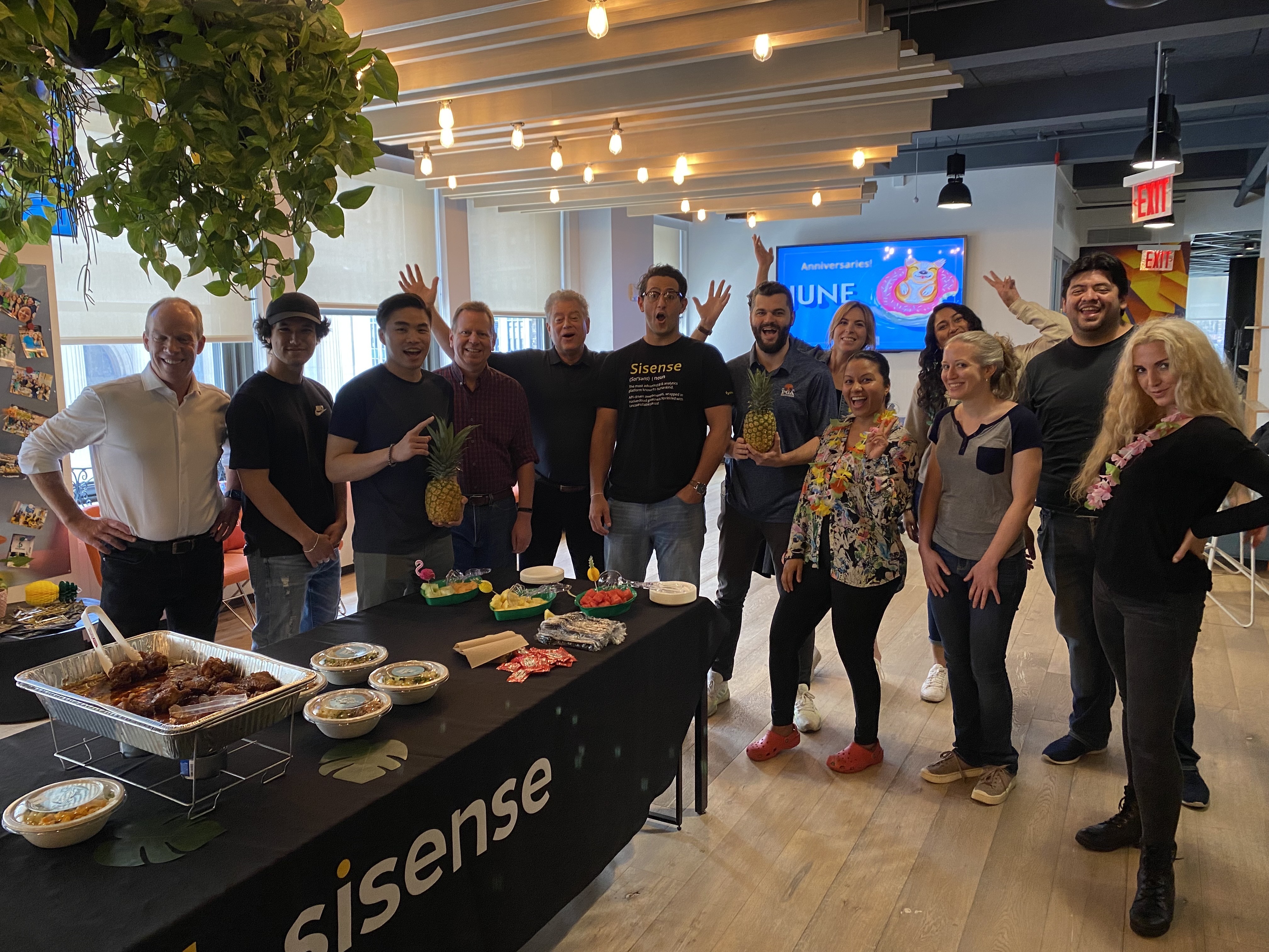 Sisense's team posing enthusiastically for a photo in front of a buffet table.