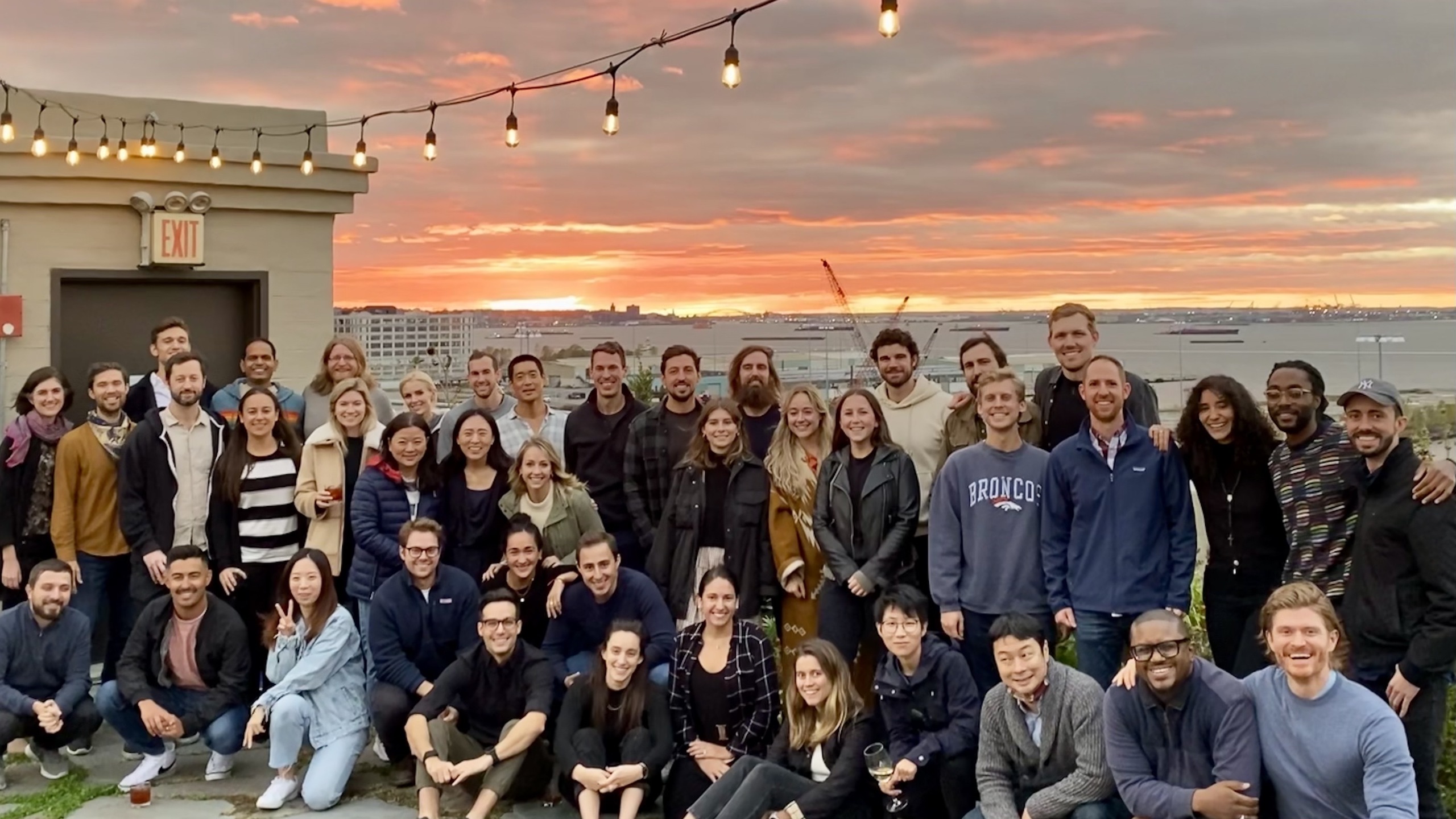 Ethic employees pose for a group photo on a rooftop at sunset. 