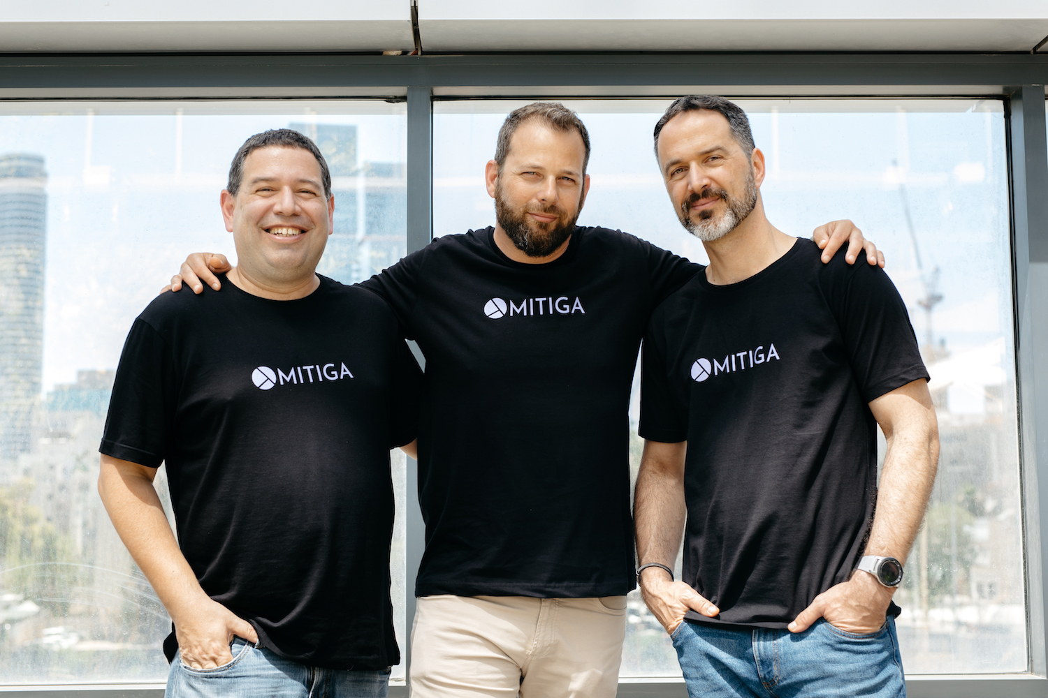 Mitiga was co-founded by CTO Ofer Maor, CEO Tal Mozes and COO Ariel Parnes. They are pictured side-by-side in front of a window.