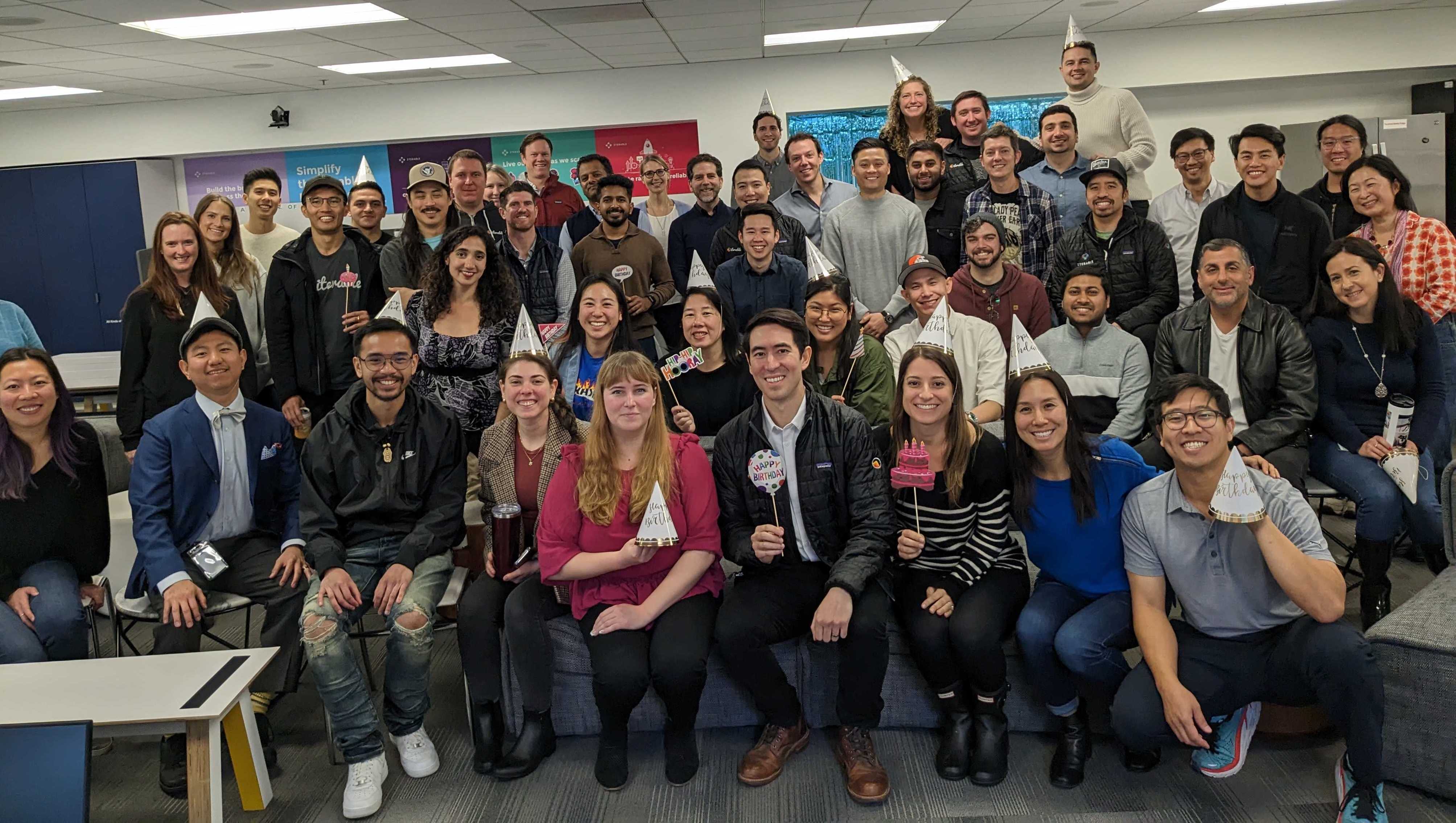 Large group photo of Iterable team members wearing party hats