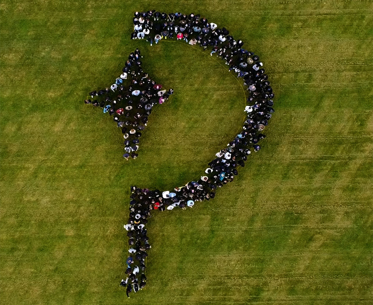 Overhead view of team members standing in the shape of the Paddle logo