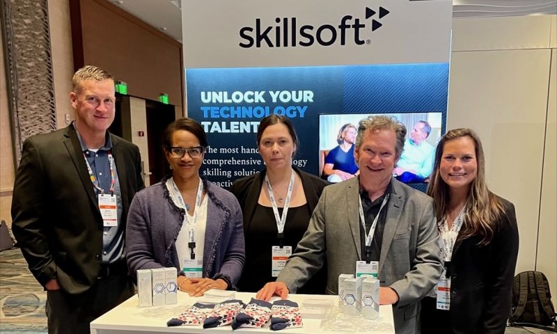 Team members stand at the Skillsoft booth at an expo.