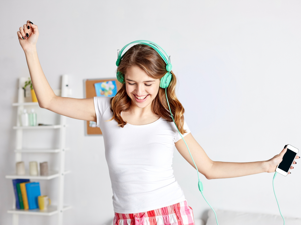 A woman wearing headphones and dancing to music