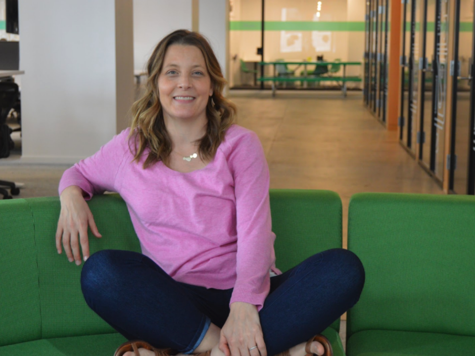 A woman in a pink shirt sits on a green couch