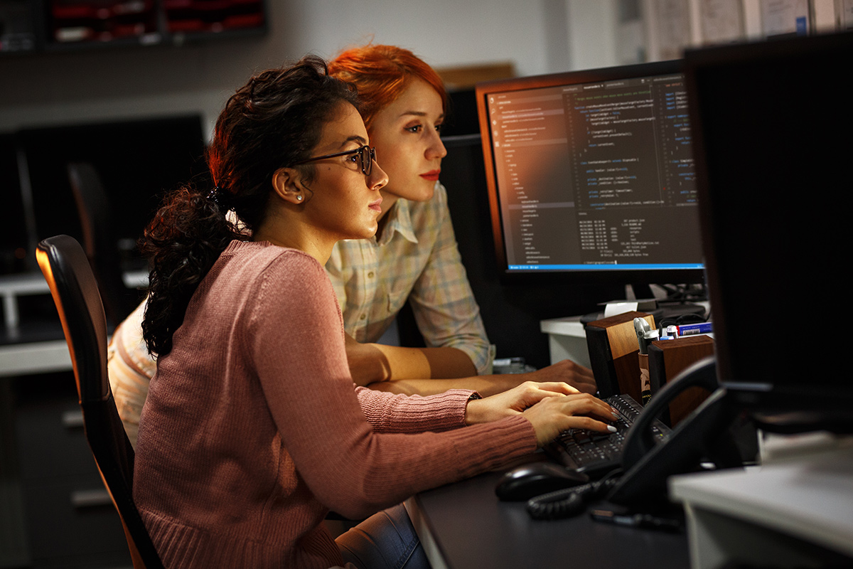 Two female programmers looking at a monitor working on a project