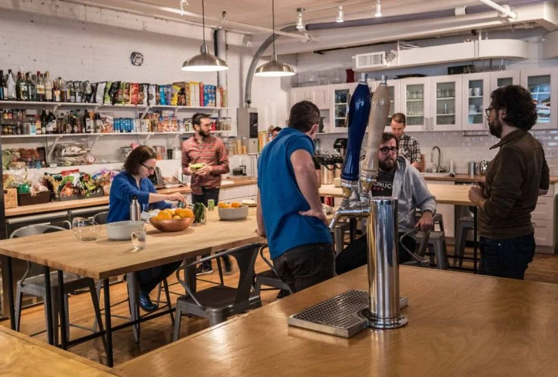A group of Betterment employees mingle in the company kitchen space.