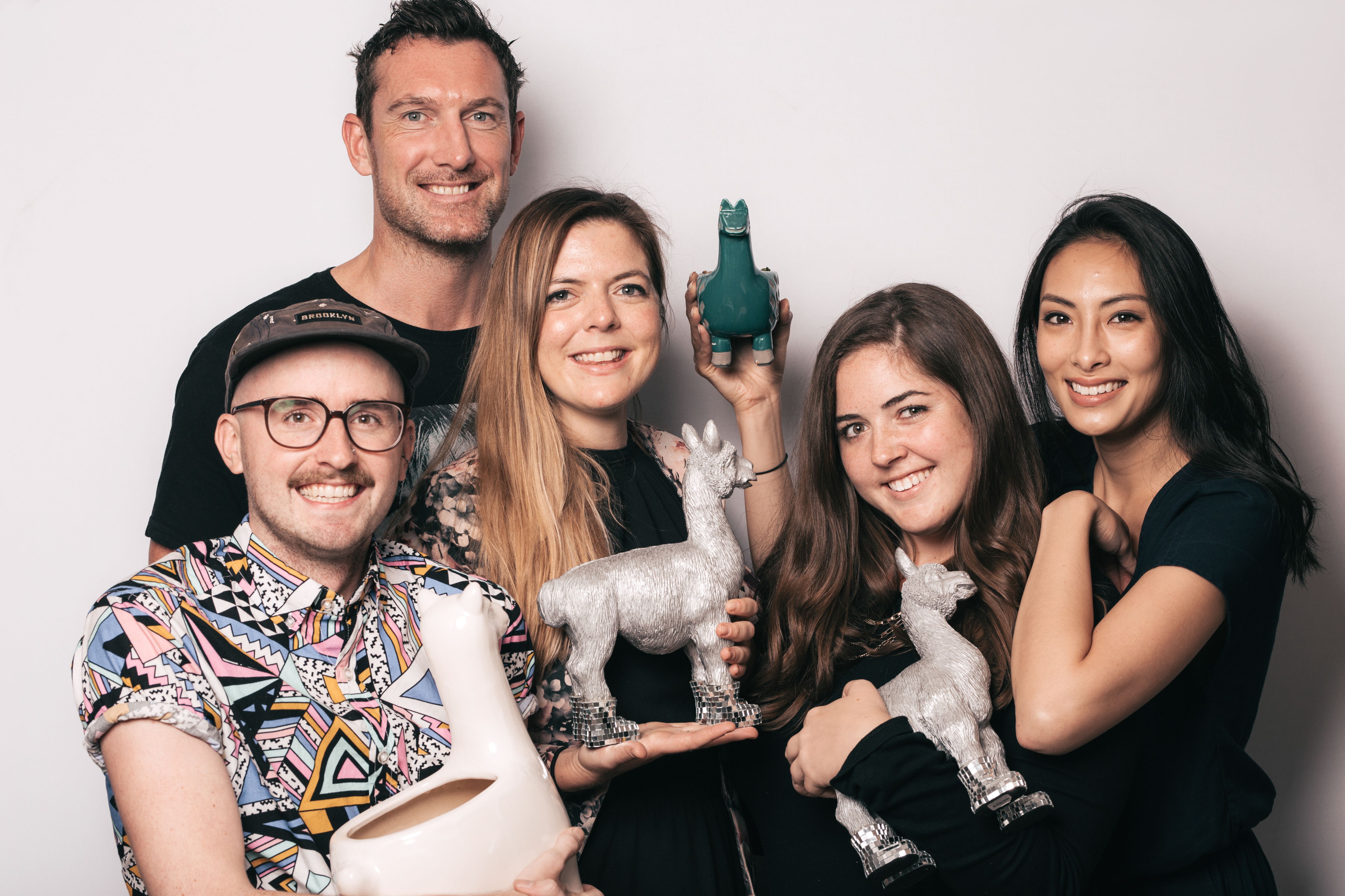 Group photo of five NextRoll employees holding llama statues.