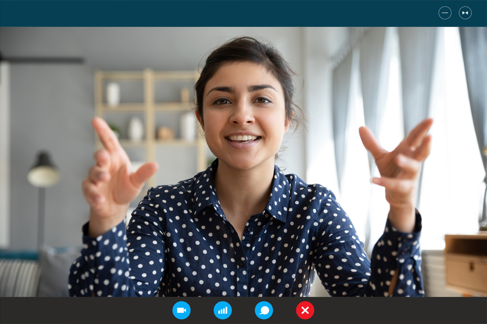 Screen view of a woman teaching virtually, smiling and talking with her hands.