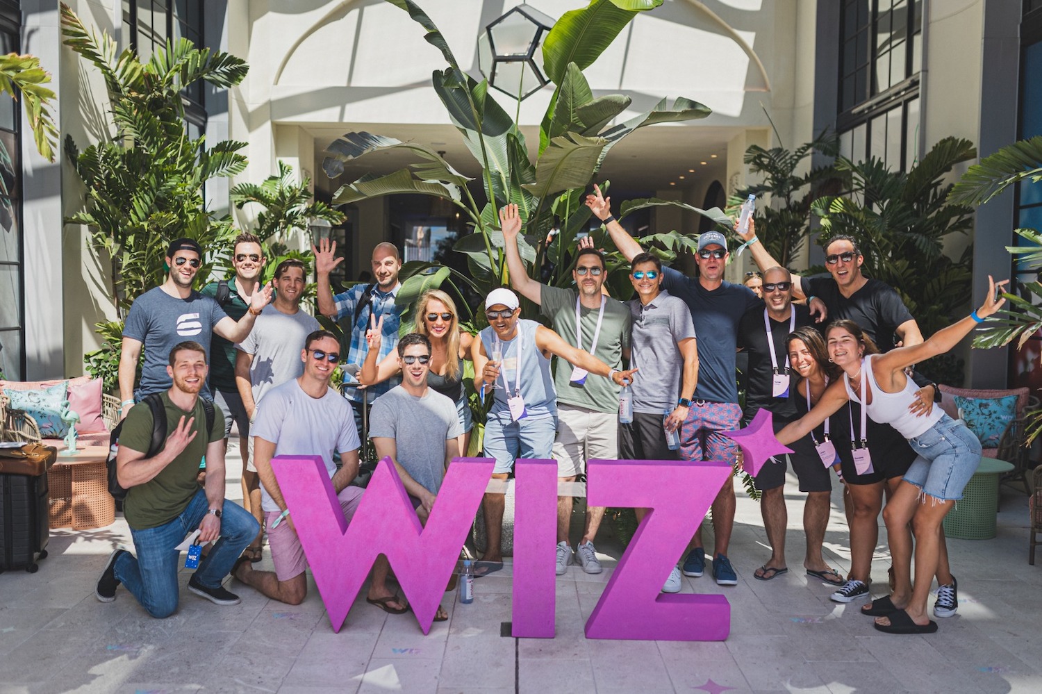 The Wiz team is pictured around a pink sculpture of the company logo.