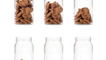 Six glass jars containing cookies but each jar progressively has less cookies until the sixth jar that is empty