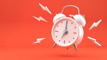 Image of a white alarm clock ringing against an orange background