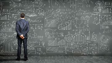 Man standing at chalkboard wall full of graphs and data