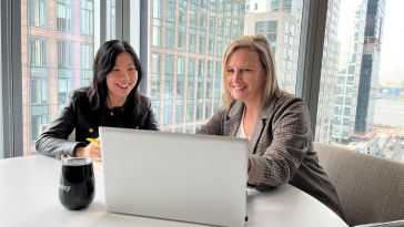 Yang Lu and Annette Hater work on a laptop together.
