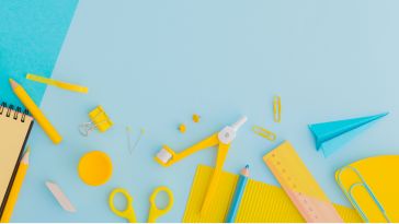 Yellow and blue desk objects (pencils, paperclips, notepads, etc.) against a blue backdrop