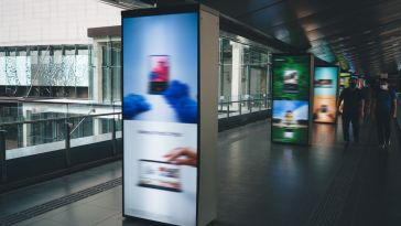 Blurred digital ads in a public walkway are pictured.