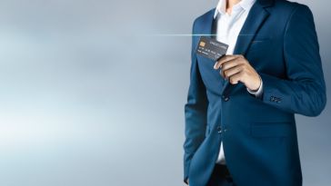 A person in a suit holding up a credit card is shown.